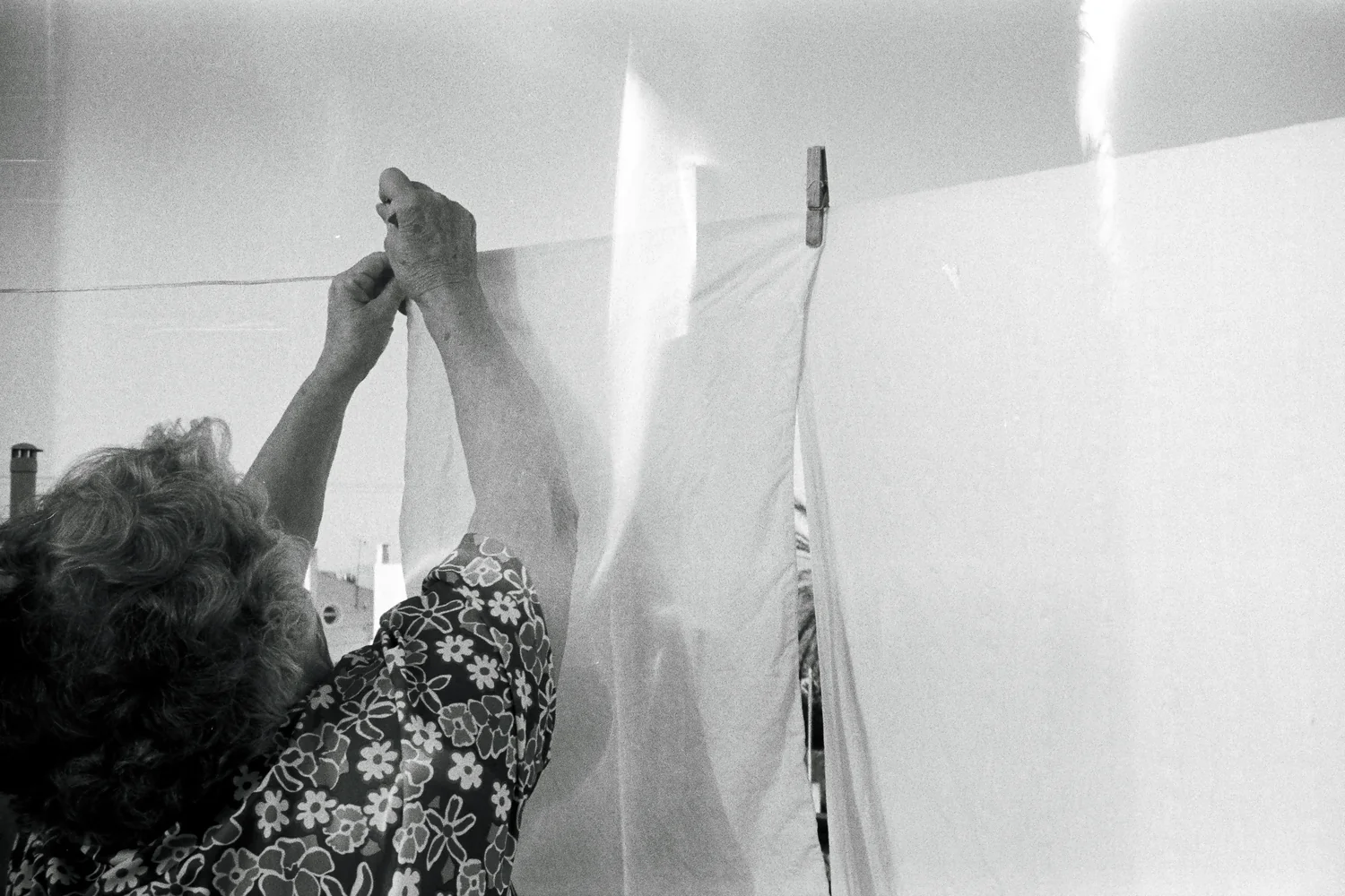 Black and white photograph of hands pegging a sheet to a washing line